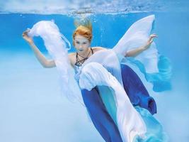 Underwater fashion portrait of beautiful blonde young woman in blue dress photo