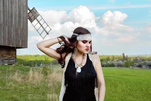 hermosa joven con el pelo largo y oscuro en el campo verde en la aldea étnica al aire libre en kiev, ucrania foto
