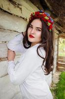 young beautiful woman with long dark hair in Ukrainian blouse and in a wreath in outdoor ethnic village in Kyiv Ukraine photo