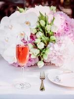 flowers and glass of rose sparkling outdoor, plate, fork, knife on the table. Cutlery, food, lunch, party concept photo