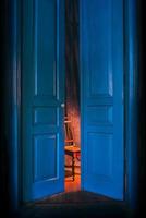 empty chair in light behind blue massive vintage doors indoor. Old fashioned interior concept photo