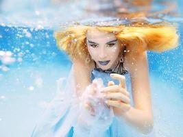 retrato de moda bajo el agua de una hermosa joven rubia con vestido azul foto