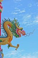 Golden flying majestic Asian Chinese dragon statue with blue sky in sunny day