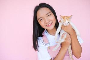 Smile young girl with cat on pink background. photo