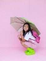 Student young girl with green umbrella on pink background. photo