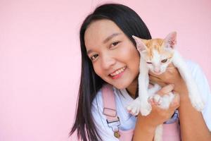 Smile young girl with cat on pink background. photo