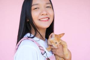 sonrisa joven con gato sobre fondo de color rosa. foto