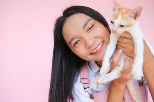 Smile young girl with cat on pink background. photo