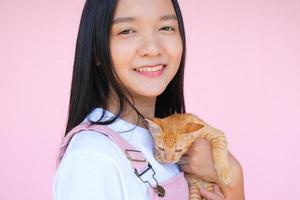 Smile young girl with cat on pink background. photo