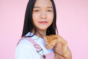 Smile young girl with cat on pink background. photo