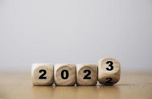 Wooden block cube flipping between 2022 to 2023 for change and preparation merry Christmas and happy new year by 3d rendering. photo