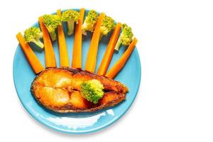 Salmon steak with carrots and broccoli in blue dish isolated on a white background with clipping path. Top view. photo