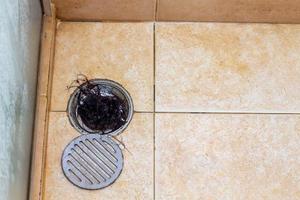 Agujero de drenaje con pelo en el baño. problemas de caída del cabello y tuberías de agua obstruidas. foto