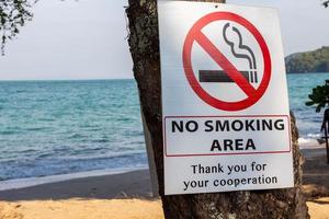 No se coloca un cartel de zona de fumadores en un árbol en la playa.