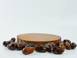 dates scattered on a round wooden plank isolated on a white background. Product display placement concept photo