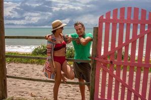 Couple leaning against a wooden fence near the beach in Caraiva Bahia, Brazil photo
