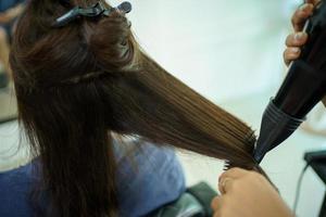 Professional hair stylist making a hair coloring and treatment in beauty and salon shop. Woman changing a hair color in professional salon shop. photo