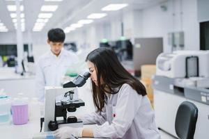 dos científicas médicas que trabajan en un laboratorio médico, una joven científica que mira el microscopio. seleccione el enfoque en una joven científica foto