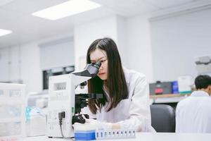 joven científica mirando el microscopio en el laboratorio médico foto