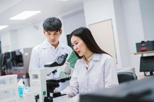 dos científicas médicas que trabajan en un laboratorio médico, una joven científica que mira el microscopio. seleccione el enfoque en una joven científica foto