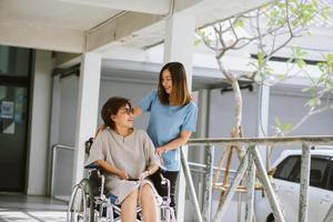 fisioterapeuta sonriente cuidando al feliz paciente mayor en silla de ruedas foto