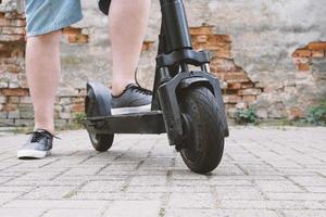 legs of unrecognizable man with electric kick scooter or e-scooter photo