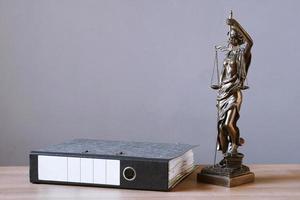 lady justice or justitia statue and file folder on desk photo