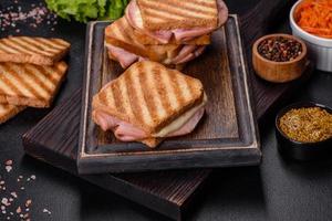 deliciosa parrilla de tostadas frescas con queso y jamón. sándwiches, merienda rápida foto