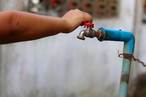 Young hand turning off water tap photo