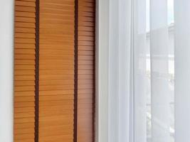 cortinas transparentes blancas con tela translúcida y persianas de madera colgadas en la ventana foto