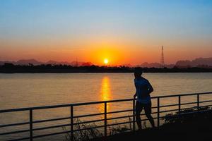 Man running on street with a view of river in the morning. photo