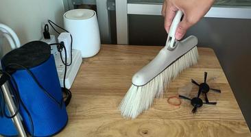 barrer el polvo a mano con una escoba en el concepto de limpieza de la mesa de madera foto