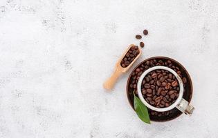 Roasted coffee beans with scoops setup on white concrete background. photo