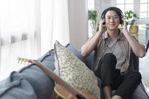 An asian man is listening Music in living room . photo