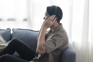 An asian man is listening Music in living room . photo