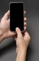 close up hand holding smart phone over black background studio photo