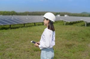 Female engineer wearing helmet in Photovoltaic Cell Farm or Solar Panels Field, eco friendly and clean energy. photo