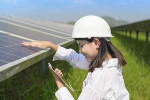 ingeniera con casco en granja de células fotovoltaicas o campo de paneles solares, energía ecológica y limpia. foto