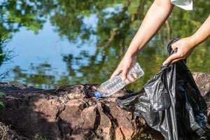 A woman cleans up by picking up plastic bottles at a natural water reservoir. Concept of protecting the environment, saving the world, recycling, reducing global warming. close up, blurred background photo