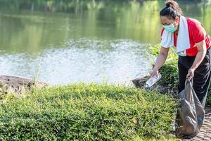 Woman cleans up by picking up plastic bottles at a natural water reservoir. Concept of protecting environment, saving world, recycling, reducing global warming, Earth Day. close up, blurred background photo