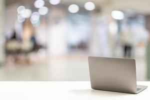 The back of the laptop is blank, placed on a white desk in an office, and nobody. Technology work concept, smartphone, notebook, internet, left side copy space, close up, Blurred background. photo