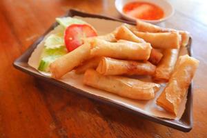 rollitos de primavera de cerdo crujientes con salsa de chili dulce sobre una mesa de madera. foto