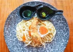 Creamy spaghetti pasta with prawn tempura and salted duck egg searved with wasabi shoyu sauce. photo