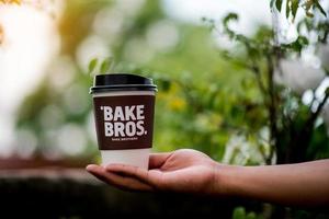 una taza de café se coloca en las manos y en el suelo con un asedio verde natural. área comiendo café en el trabajo taza de café con leche foto