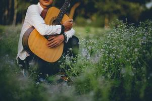 The man's hand plays the acoustic guitar, plays the guitar in the garden alone, happily and loves the music. photo