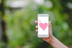 Hands and phones Pink heart screen Green nature Technology Concepts And to do business online. photo