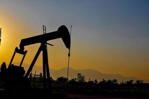 plataforma petrolera la fuente del petróleo del subsuelo para traer el fuego. en la vida humana, silueta negra y puesta de sol negra. foto