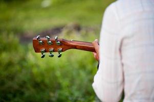 The man's hand plays the acoustic guitar, plays the guitar in the garden alone, happily and loves the music. photo