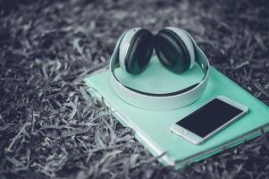 Hands and headphones are placed next to each other in green grass and moody music. Concepts of communication and listening. photo