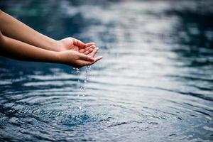 The hand that touches the blue water. The pool is clean and bright. With a drop of water on the water. photo